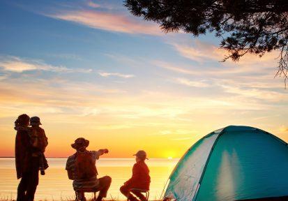 Family camping in tent with sunset in the background