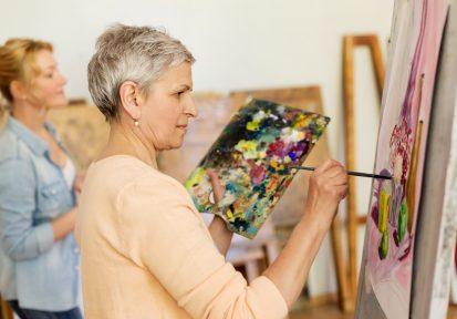 senior woman painting at art school studio