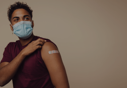 Man wearing face mask showing his vaccinated arm. Man in protective face mask received a corona vaccine