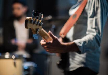 a member of a rock band at a jam session performs a musical part on bass guitar.