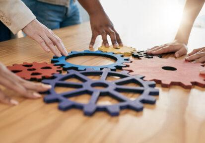 Hands placing cog puzzle pieces together. Concept of working together.
